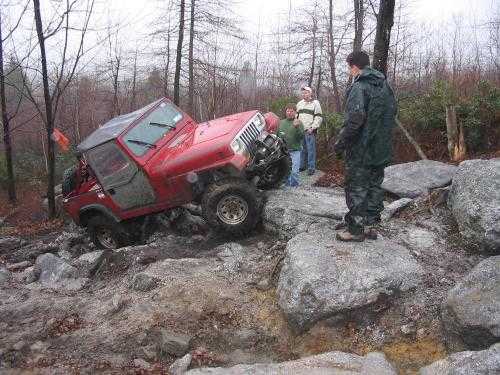 Red Jeep tackling rocky terrain, off-road adventure