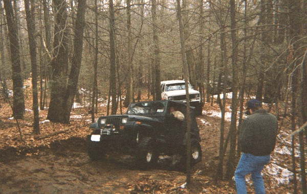 Jeeps navigating a muddy wooded trail
