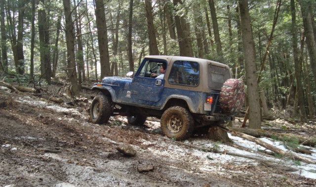 Blue Jeep navigating muddy, snowy trail