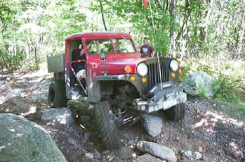 Red Jeep navigating rocky terrain
