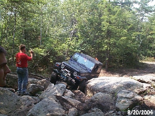 Jeep stuck on rocks; man watches