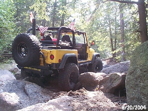 Yellow Jeep Wrangler navigating rocks