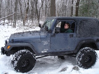 Woman driving Jeep in snowy woods