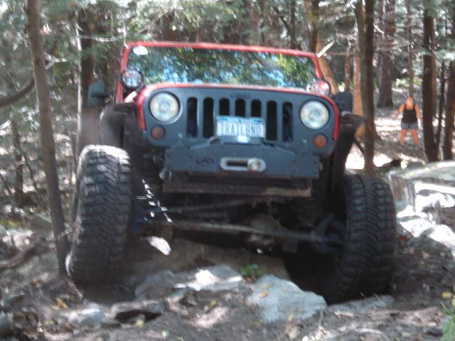 Red Jeep Wrangler navigating rocky trail
