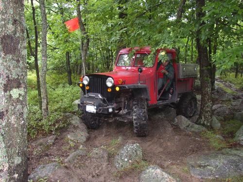 Red Jeep navigating rocky terrain