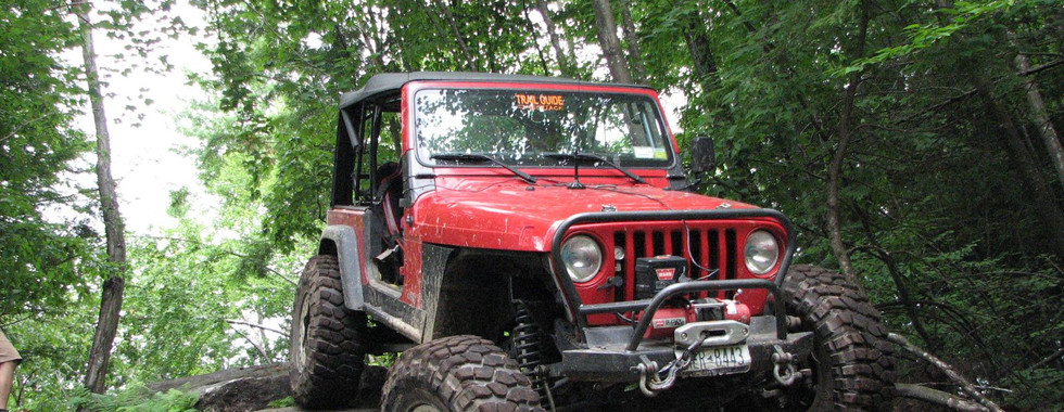 Red Jeep Wrangler off-roading on rocks