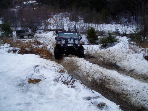 Jeep navigating snowy, muddy trail