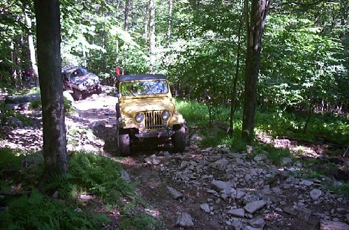 Yellow Jeep traversing rocky trail