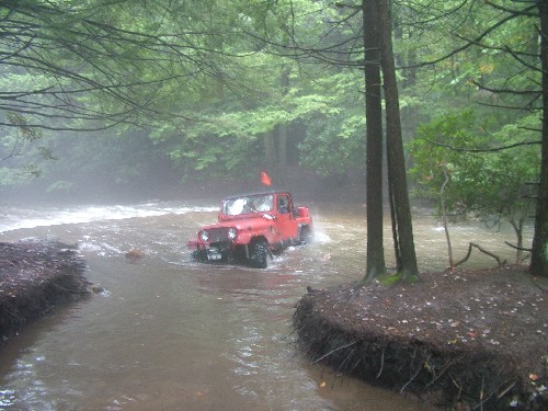 Red Jeep crossing a stream