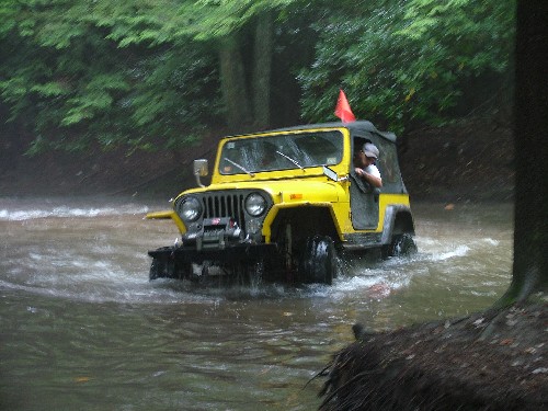Yellow Jeep traversing a flooded trail