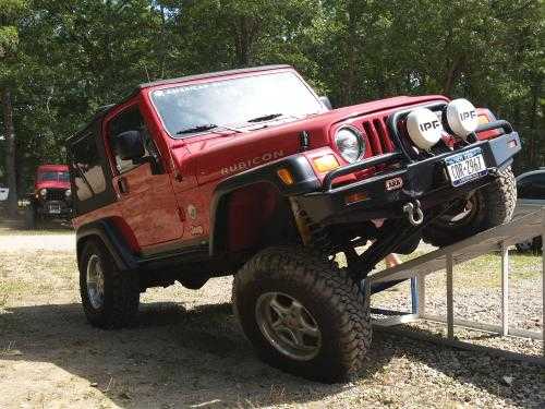 Red Jeep Wrangler overcoming obstacle
