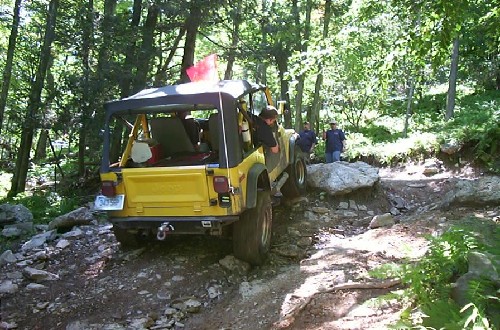 Yellow Jeep navigating rocky terrain