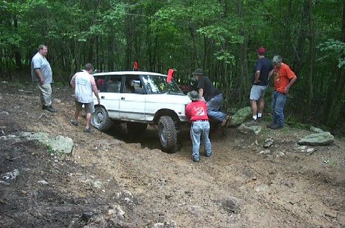 White Land Rover stuck, men pushing; off-roading