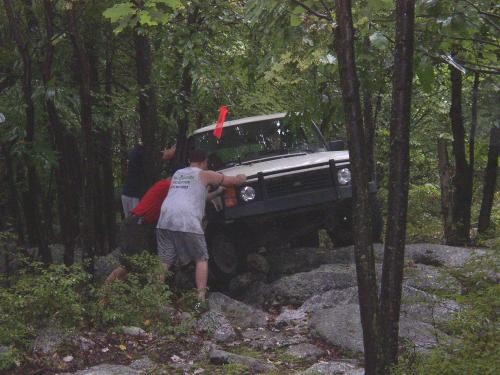 Friends pushing a stuck off-road vehicle