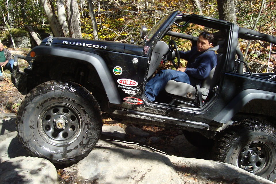 Man driving black Jeep Rubicon on rocks