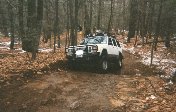 White Jeep Cherokee off-roading on muddy trail
