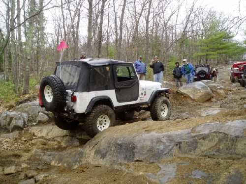 White Jeep navigating rocks; off-road adventurers watch