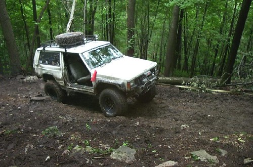 White Jeep Cherokee off-roading in woods