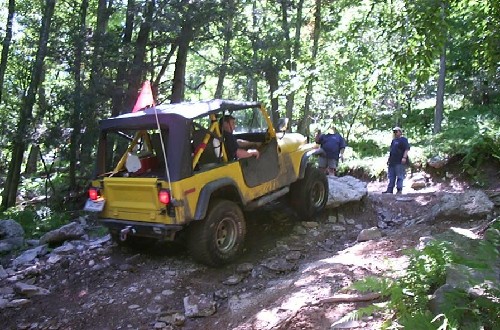 Yellow Jeep navigating rocky trail
