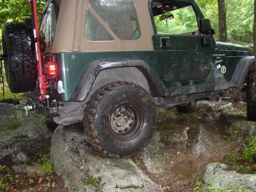 Green Jeep Wrangler traversing rocks