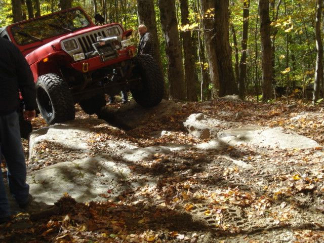 Red Jeep ascending rocky trail