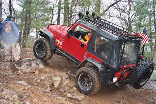 Red Jeep traversing rocky terrain