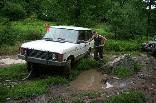 Woman beside white Range Rover in mud