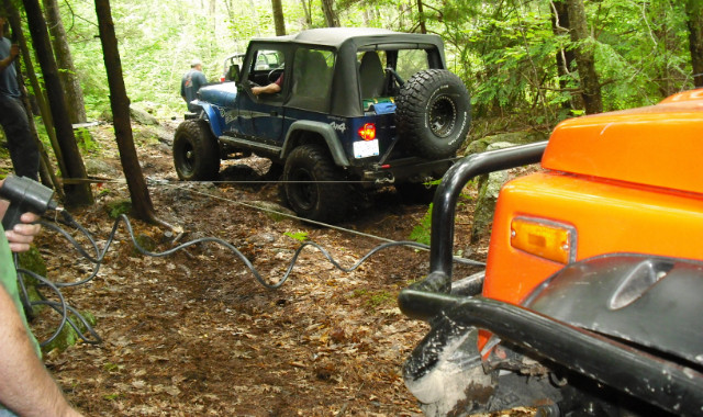 Jeeps on wooded trail, one pulling another