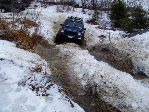 Jeep navigating snowy, muddy trail