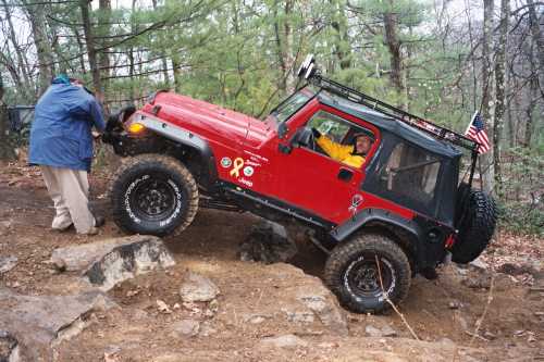 Red Jeep navigating rocks; off-road adventure