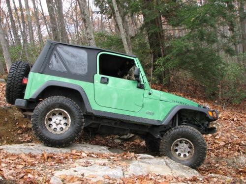Green Jeep navigating rocky terrain