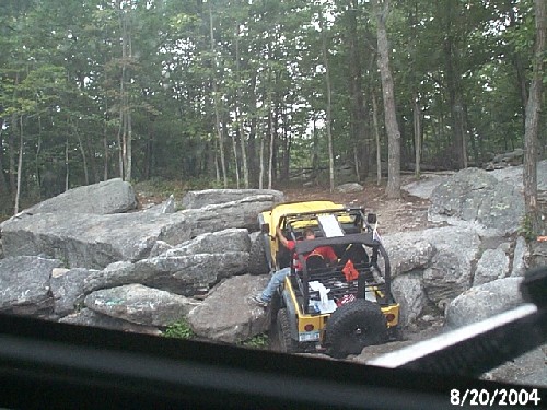 Yellow Jeep navigating rocky terrain