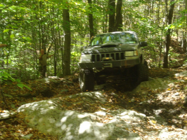 Jeep navigating rocky trail in woods