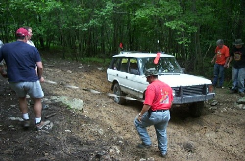 Two men pulling a white Land Rover stuck in mud