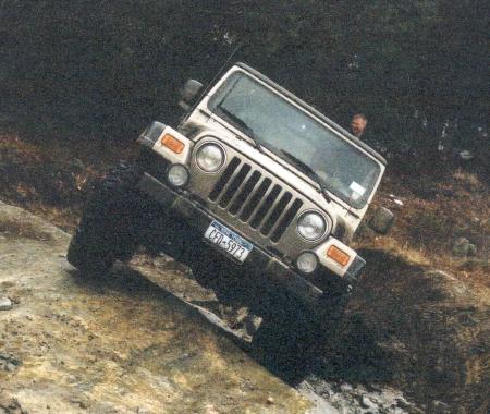 Person driving tan Jeep Wrangler on trail