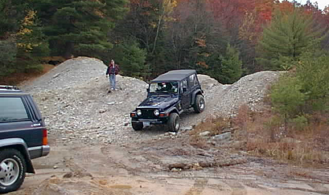 Jeep ascending rocky hill, autumn foliage