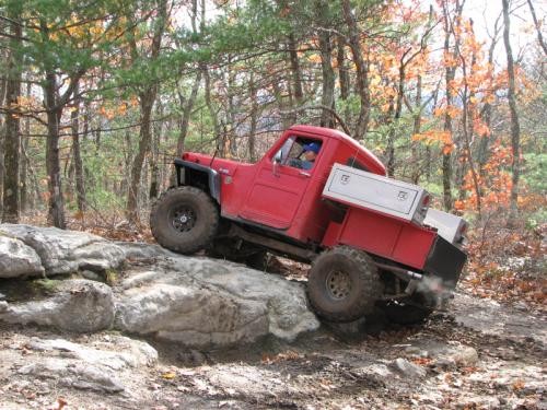 Red Jeep traversing rocks on trail