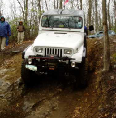 White Jeep navigating muddy trail