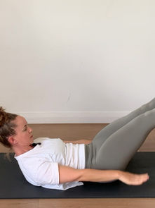 A woman performing a Pilates exercise on a mat