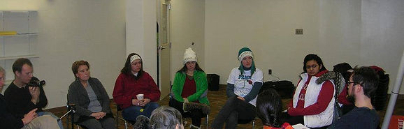 Group of people sitting in chairs in a circle talking