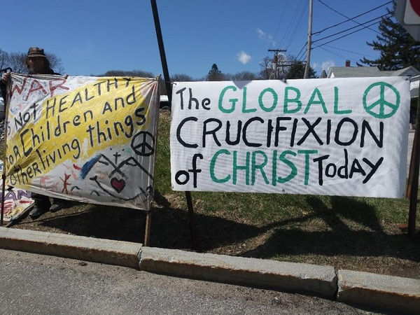 Peace signs at a protest outside shipyard saying War is not healthy for Children and other living things and the global crucifixion of Christ today