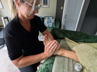 Reflexologist working on client's left foot