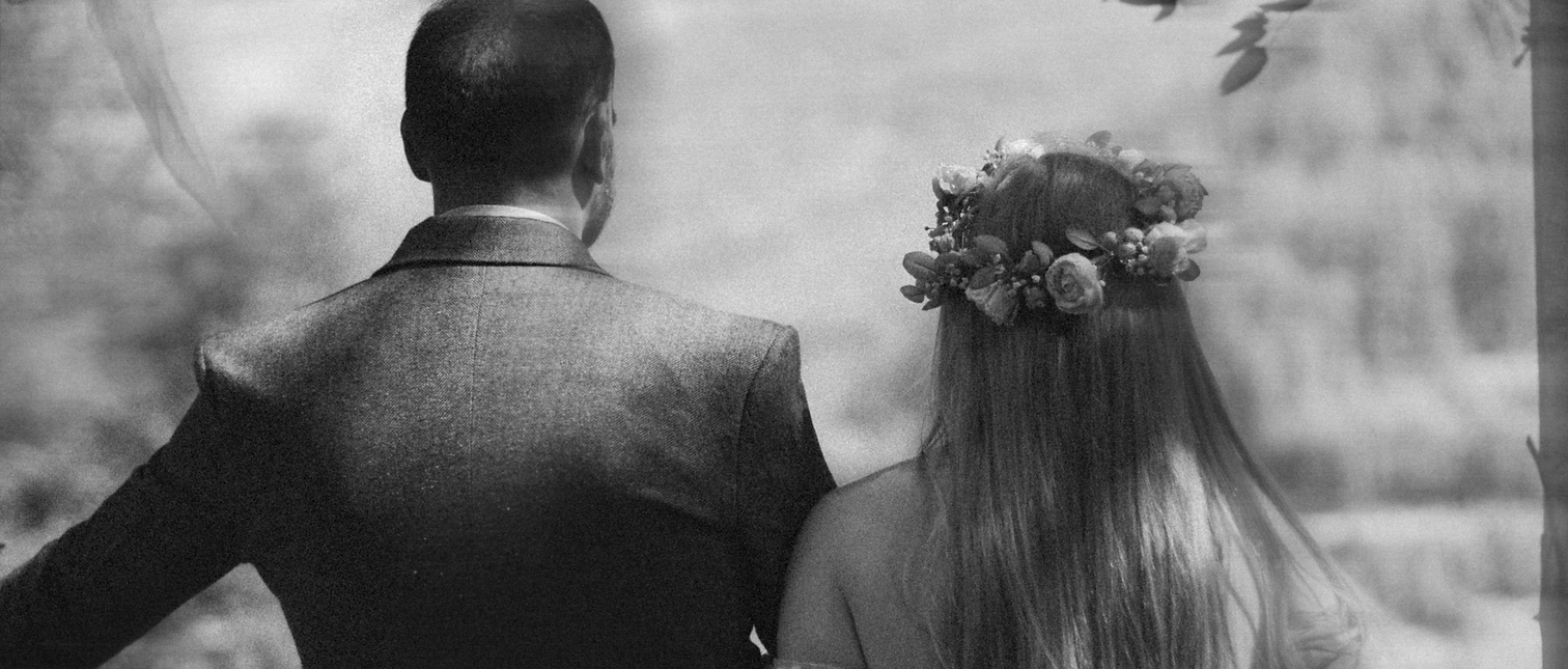 Couple, bride and groom look out over hillside view in the highlands of Scotland
