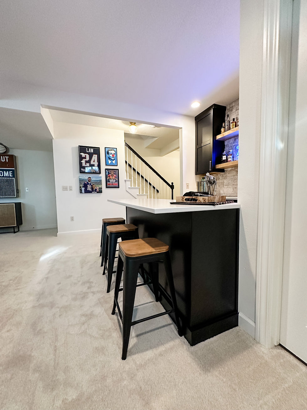 basement bar with black cabinets, white countertops