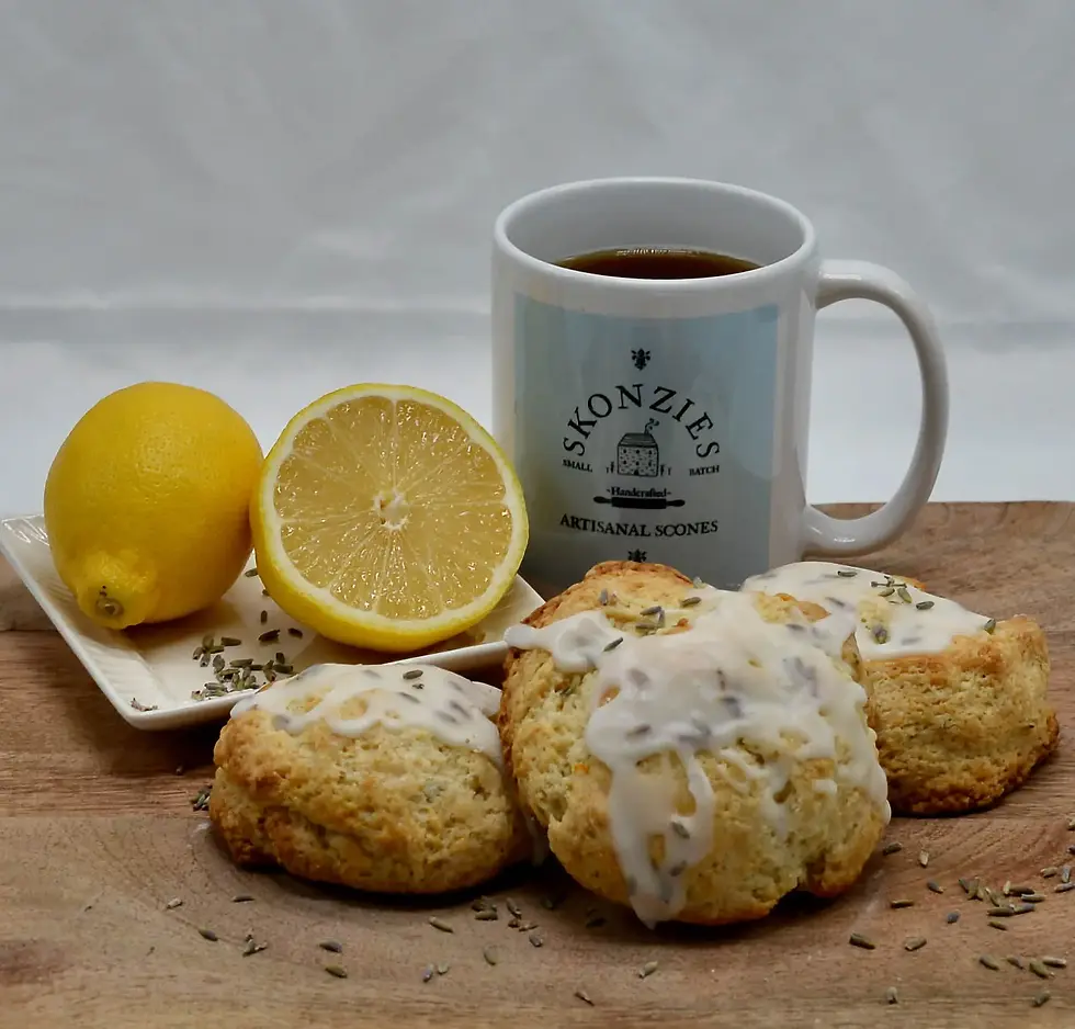 Lemon lavender scone on a table with a mug of coffee with a lemon on a plate and scattered lavender seeds