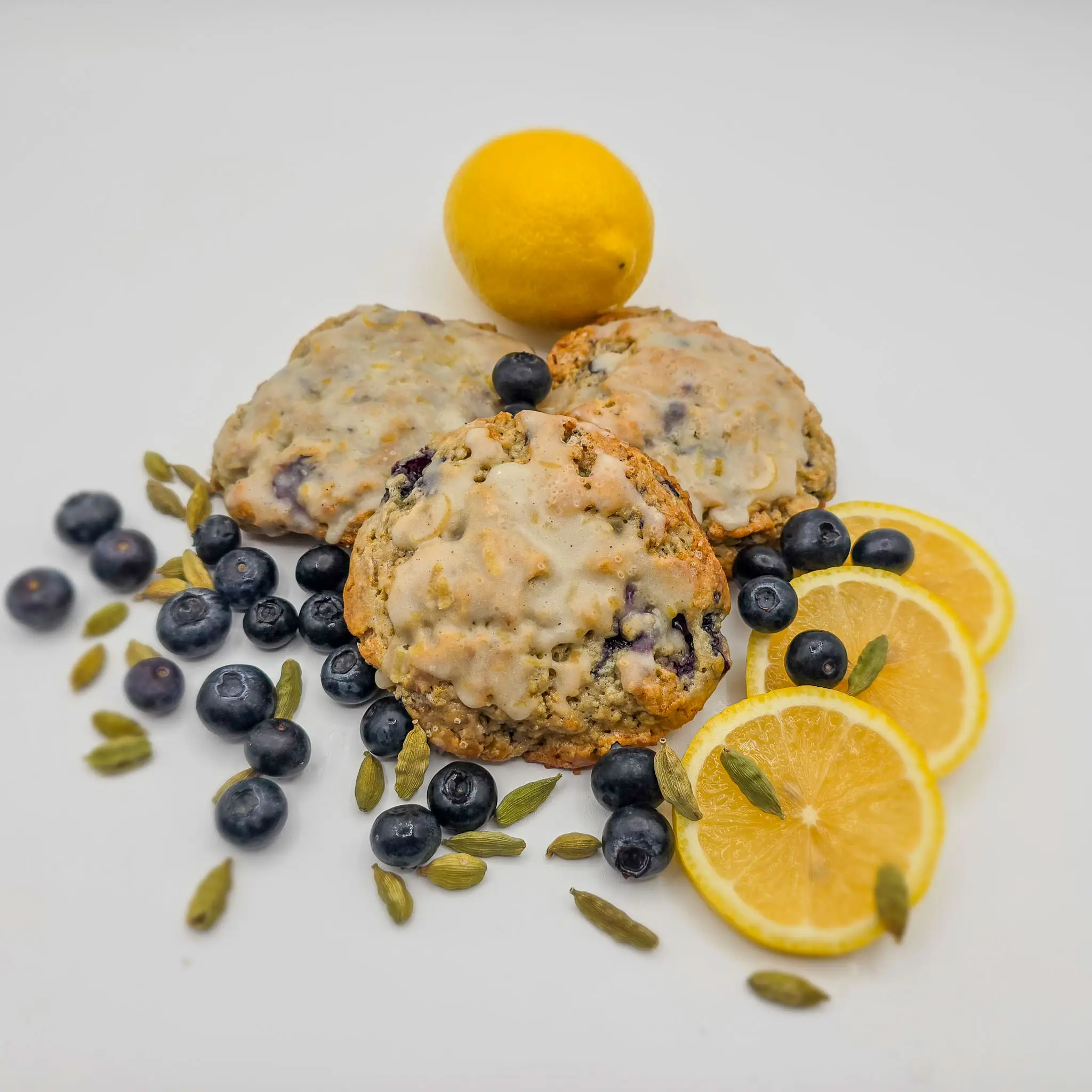 Blueberry, scone, surrounded by lemons, cardamom seeds, and blueberries