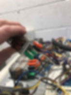 Hand holding electrical component with wires attached inside electrical cabinet