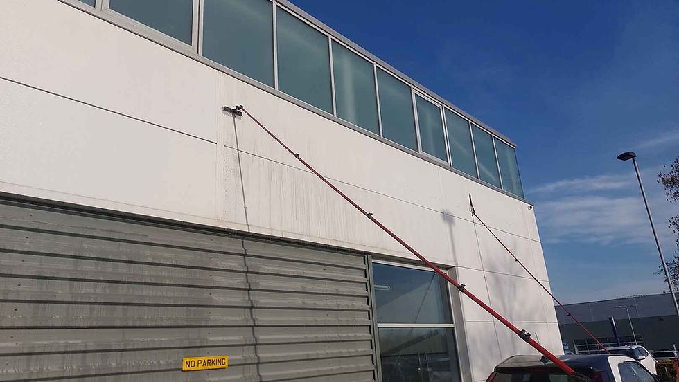 Long red pole cleaning the white exterior of a commercial building