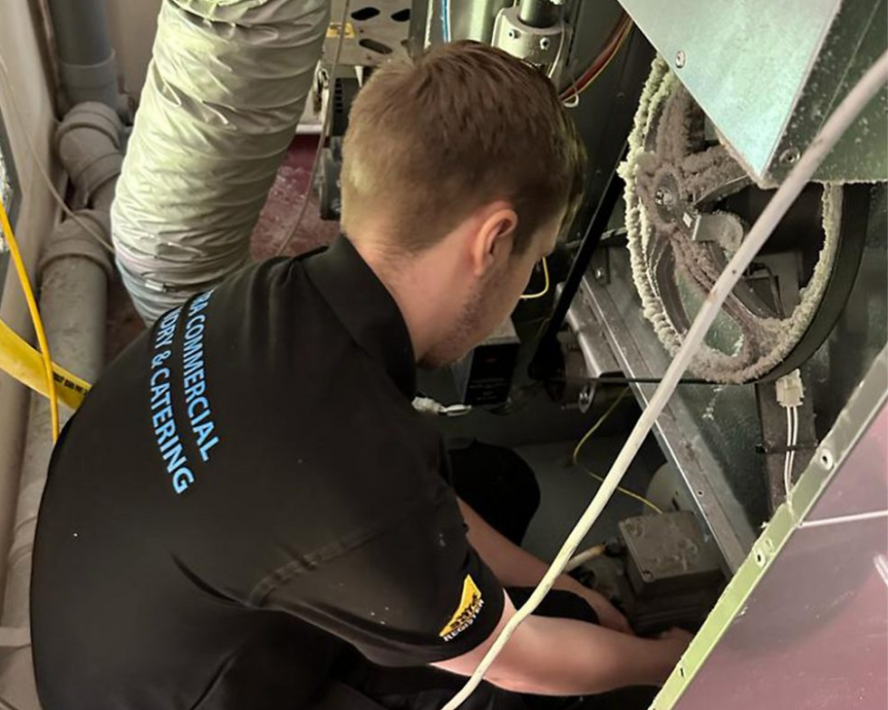 Technician performing commercial laundry repairs on a machine.