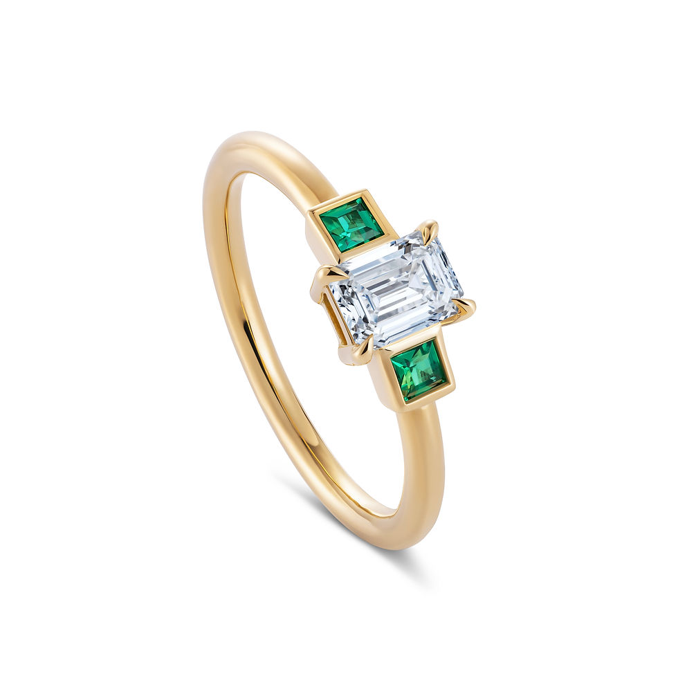 Featuring three exquisite gemstones: a dazzling round-cut diamond at the center, flanked by two vibrant green emeralds